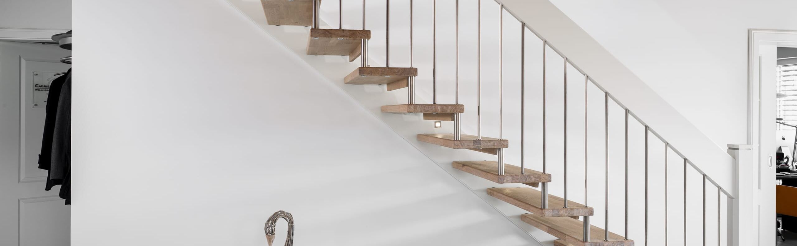 Gerade freitragende Treppe, Stufen in der Holzart Eiche mosaik weiß geölt, Geländerstäbe und Distanzrollen aus Edelstahl, Handlauf weiß endlackiert