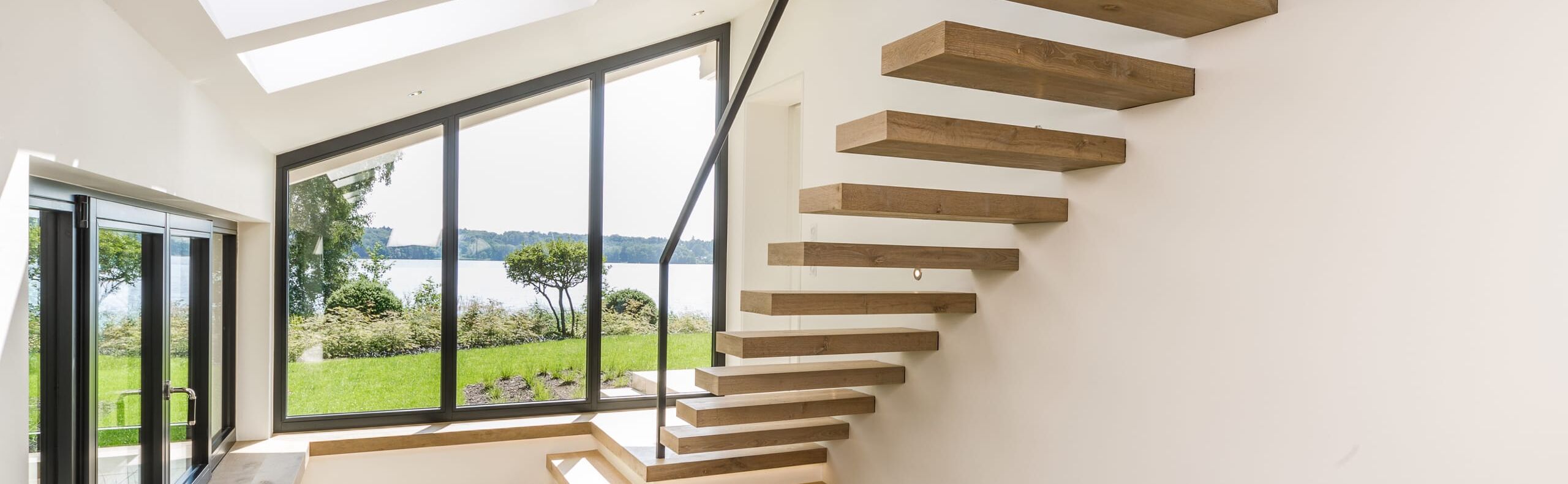 Kragarmtreppe in der Holzart Eiche astig weiß geölt mit Stahl-Designgeländer, LED-Stufenbeleuchtung und im Boden eingespannte Ganzglasbrüstung. (Architekt: Benjamin Seidel, HH)